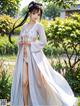 A woman in a white kimono standing in a garden.